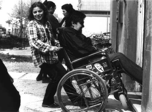 Una ragazza aiuta un handicappato in carrozzina a superare un gradino